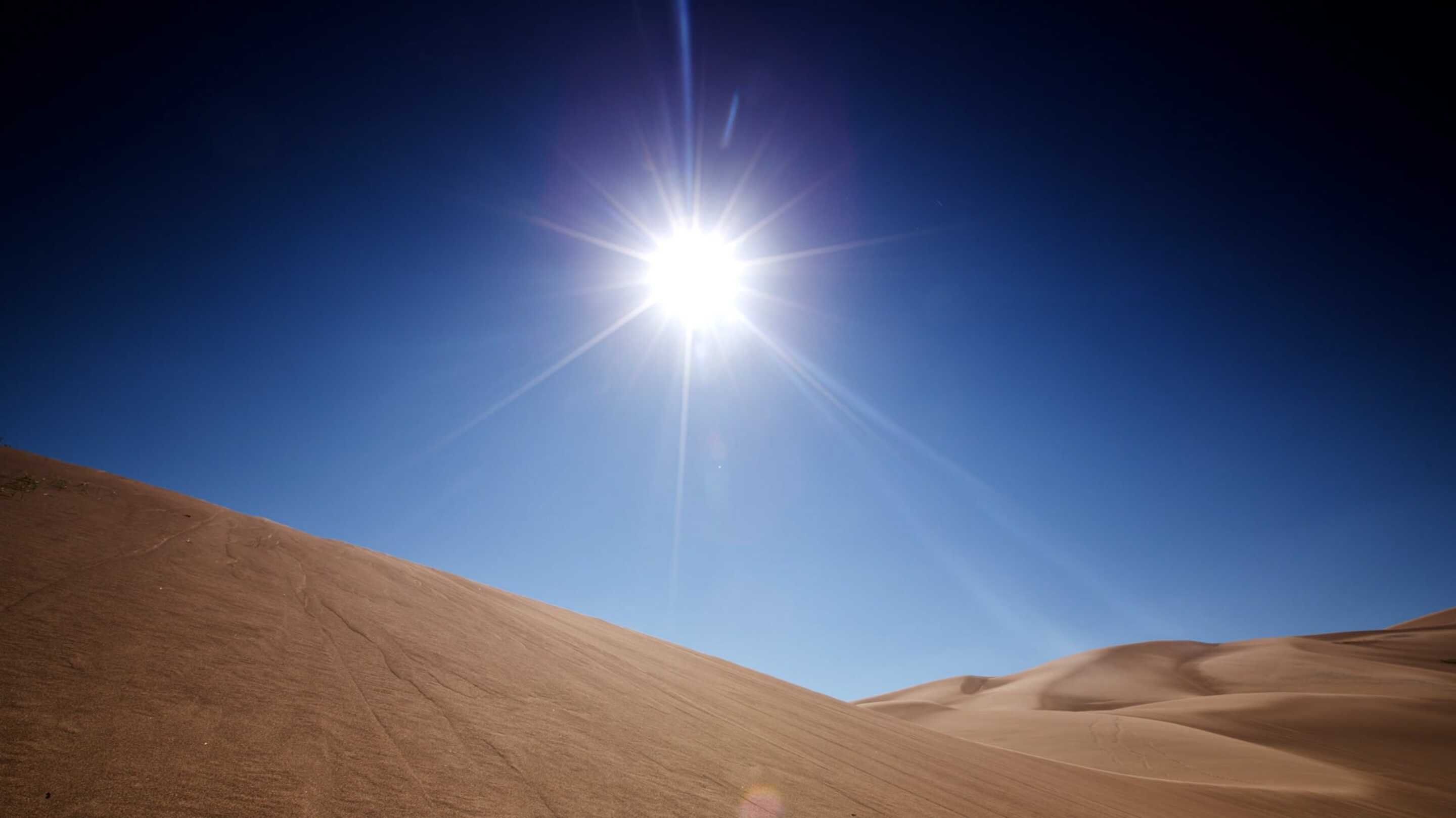 Pekskärm för utökad temperatur En sol som skiner över en sandig kulle